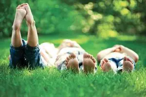 Children lie on the grass with their bare feet in the air