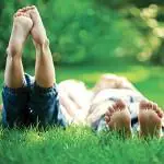 Children lie on the grass with their bare feet in the air