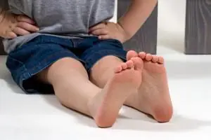 A young child sits with bare feet, the soles facing the camera
